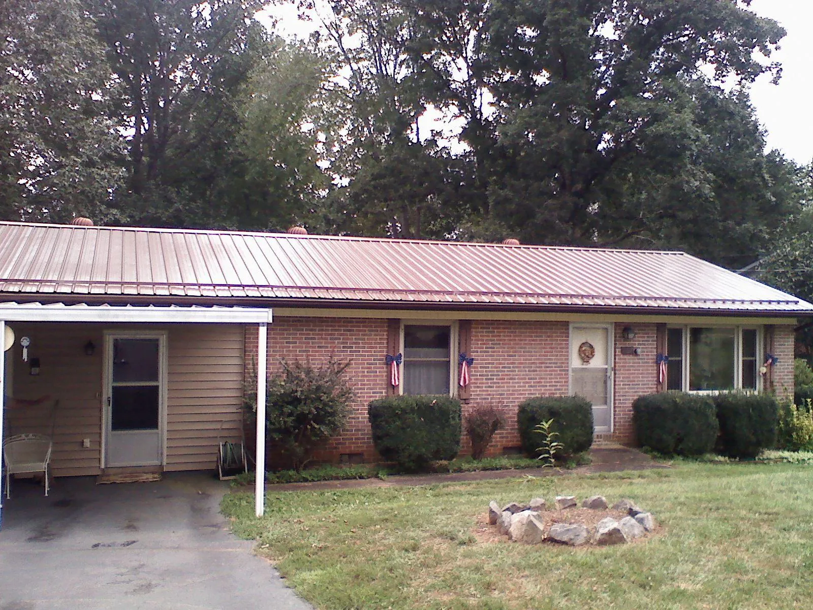 Bronze metal roof and carport on a brick ranch home — Roof Repair work by our crew in Amherst