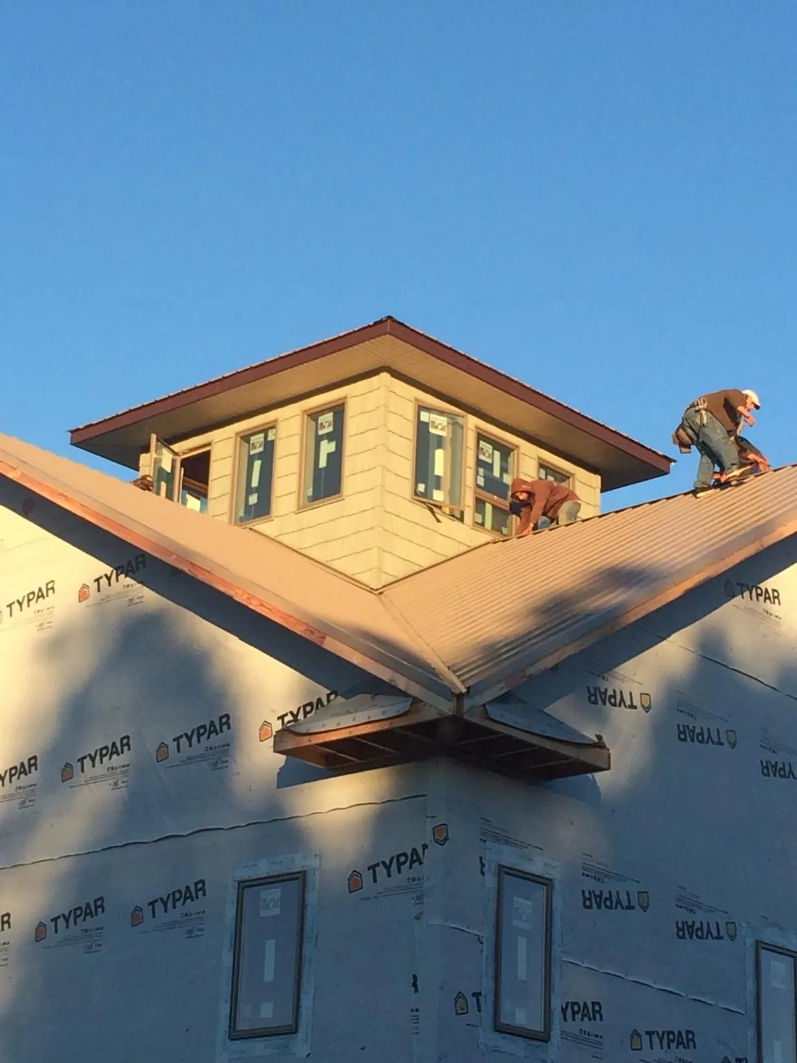 Roofers working around a rooftop cupola on a new metal roof at sunset — Roof Waterproofing in Amherst by Roofing Brothers